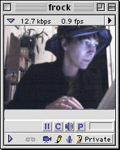 An old school GUI grey media player with a square screen of a woman wearing a hat staring at a screen with blue light reflecting back on her face, cosily typing away. A bookshelf with a plant is shown in the background.
