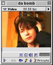 An old school GUI grey media player with a square screen of a woman holding headphones up to her face, gazing romantically at the bottom left of the screen. The sun shins partially on her face, creating a warm orange filter.