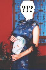 A photo of a person wearing a royal blue floral mandarin gown and a black feather boa while holding a small drawing in front of a red wall with ancient Chinese carved wooden windows. The face is filled in white with typed question and exclamation marks.
