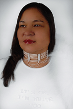 portrait of an indigenous women wearing all white wearing an ornate necklace