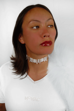 portrait of an indigenous women wearing all white wearing an ornate necklace