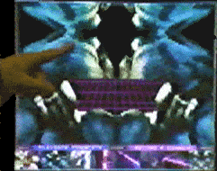 Square monitor of white and blue erotic rorsarch-like body placed on a black background. A purple space grid and two hip bones placed right underneath the opening of the yoni. A finger strokes the on-screen body. A grid of several images line the bottom.