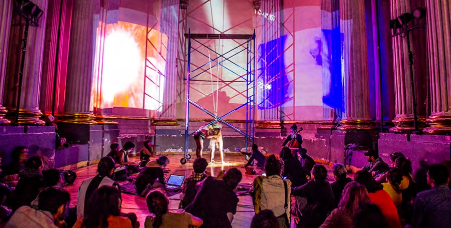 installation of a white cathedral with columns and scaffolding in the center surrounded by seated people