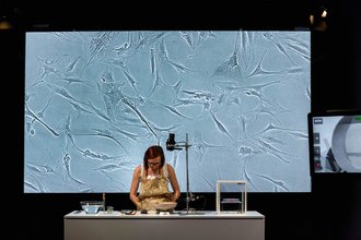 a woman stands in front of a table with surgical equipment with a gray projection behind her