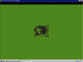 Screenshot of a vintage Microsoft webpage. A hand mouse icon hovers over the center of a green filtered square photo blending into the green background showing a seductive woman with dark curly hair, bare shoulders and collarbone, lying on the floor.